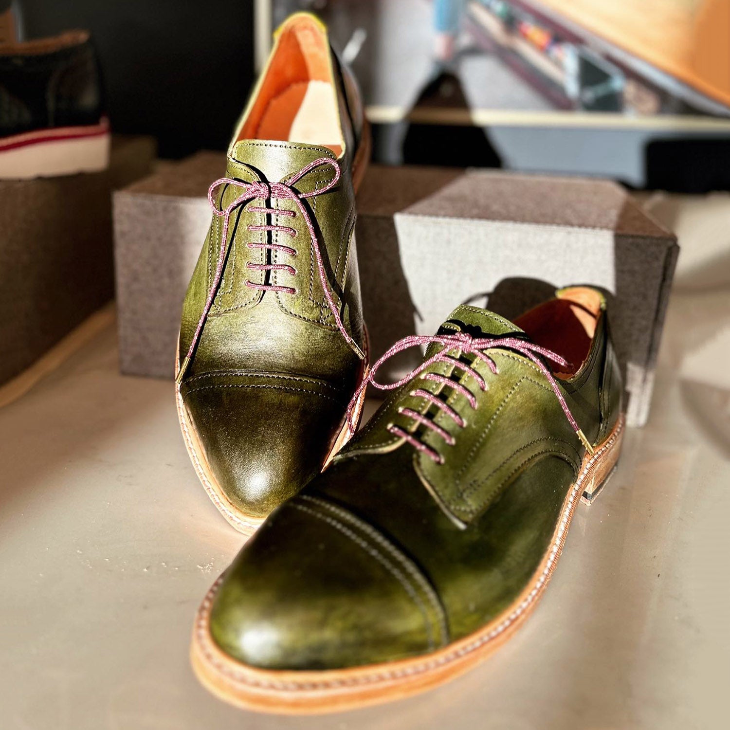 Olive green custom hand made leather derbie shoes by Leolo, with sun shining on them.