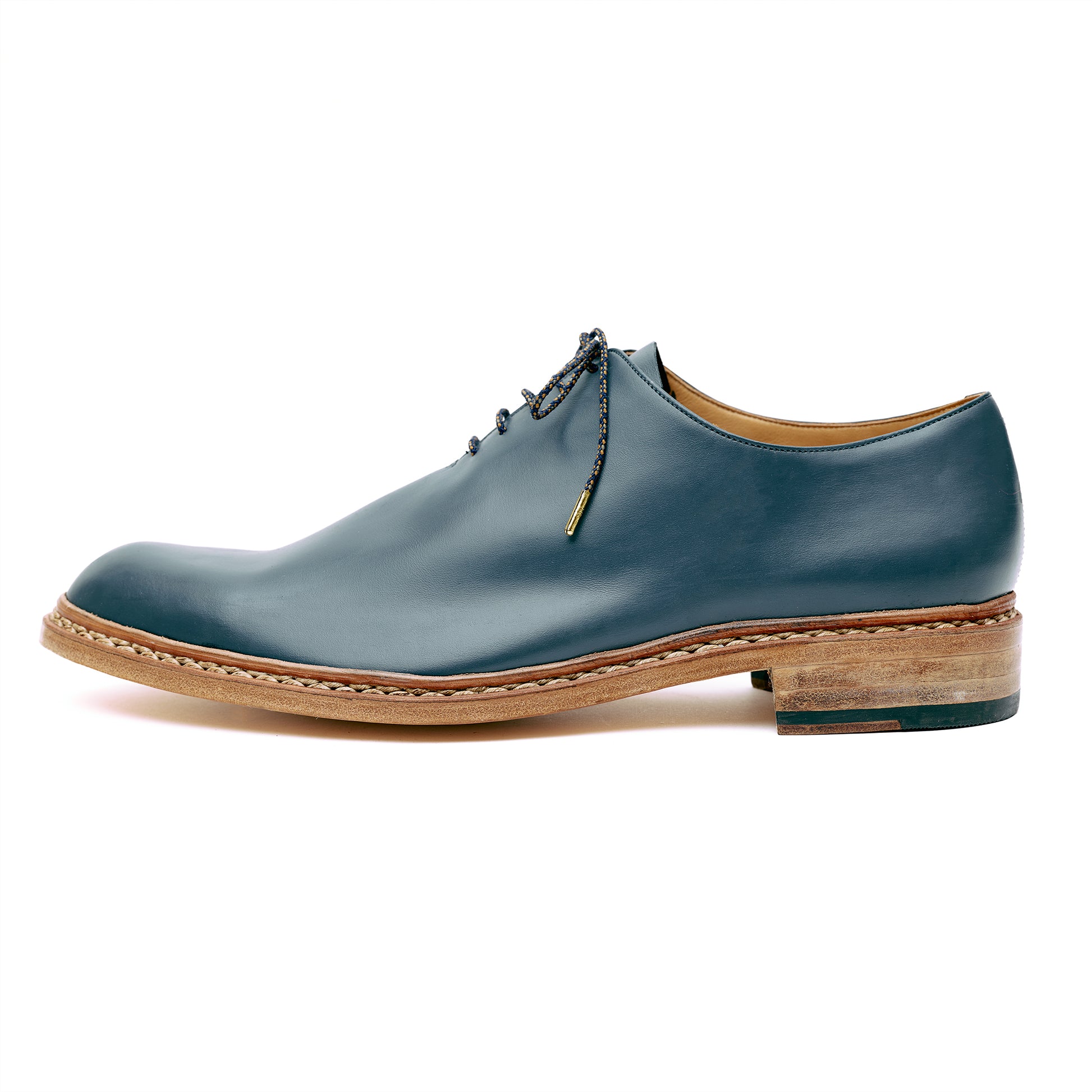 Navy blue leather custom whole cut shoes in front of white background. 