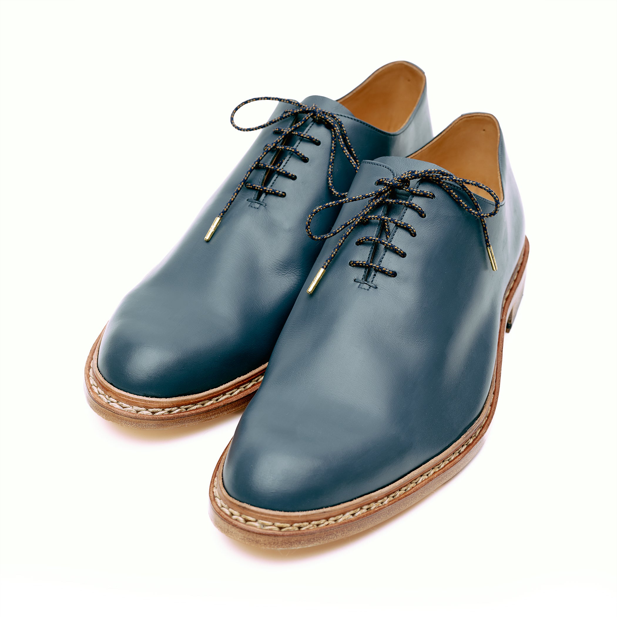 Navy blue leather custom whole cut shoes in front of white background. 
