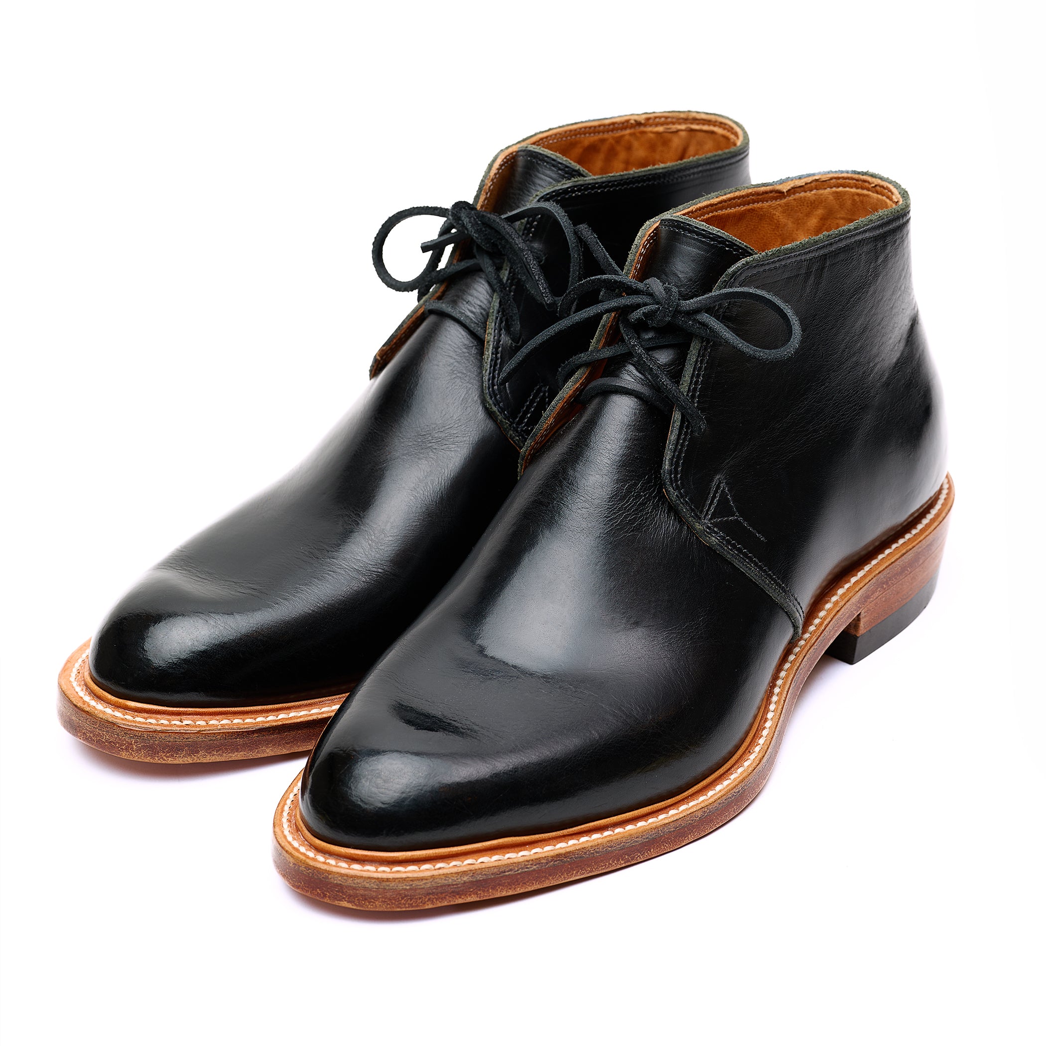 Handmade bespoke black leather Chukka boots on white background. 