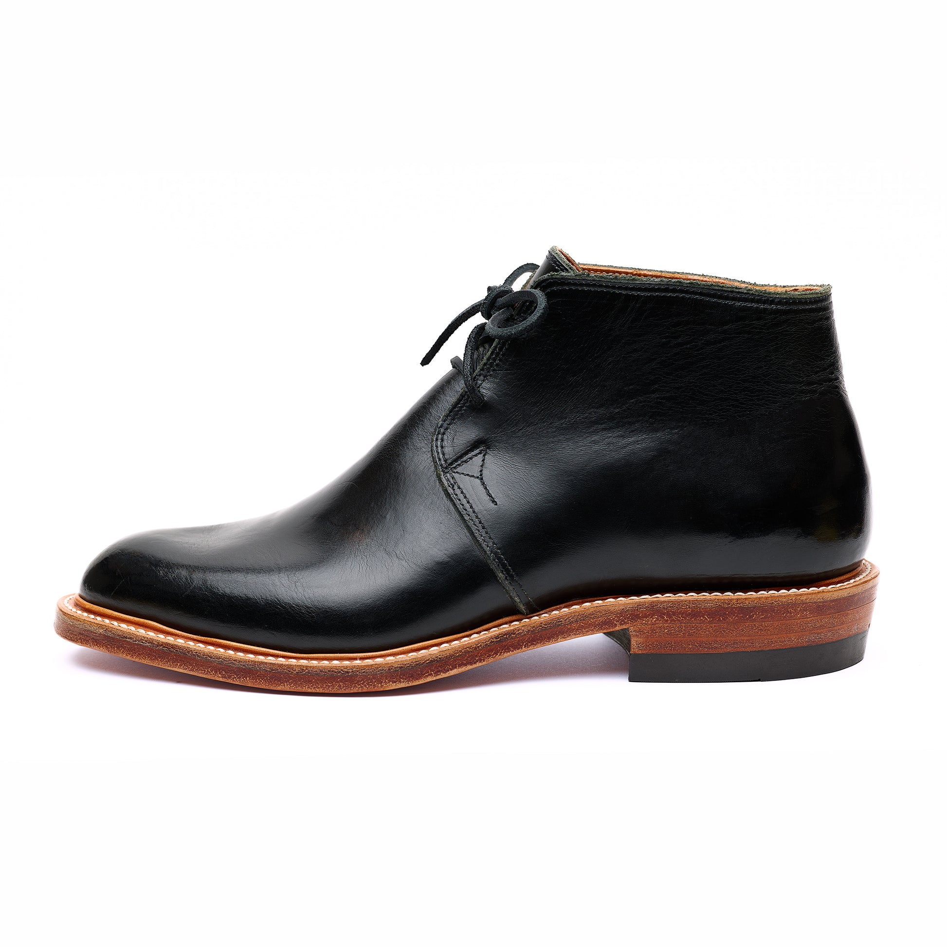 Side view of bespoke black leather Chukka boots on white background. 