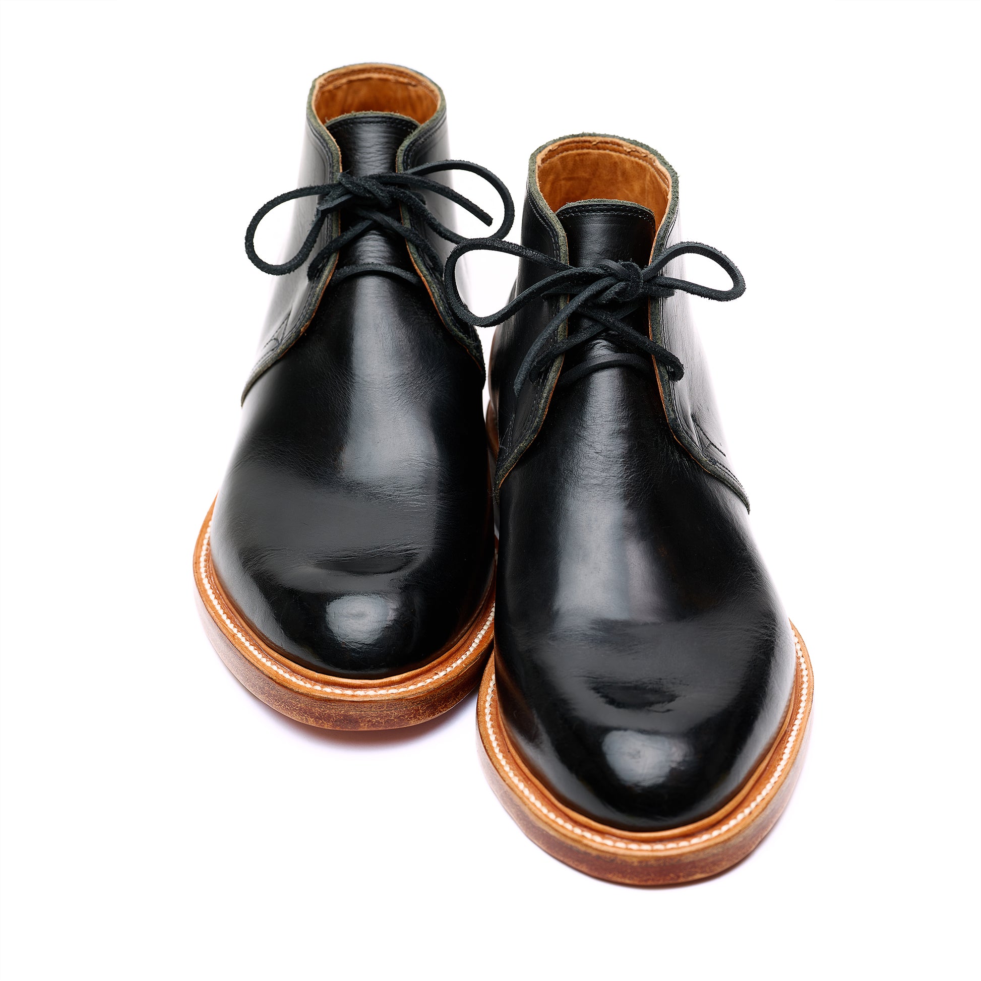 Handmade bespoke black leather Chukka boots on white background. 