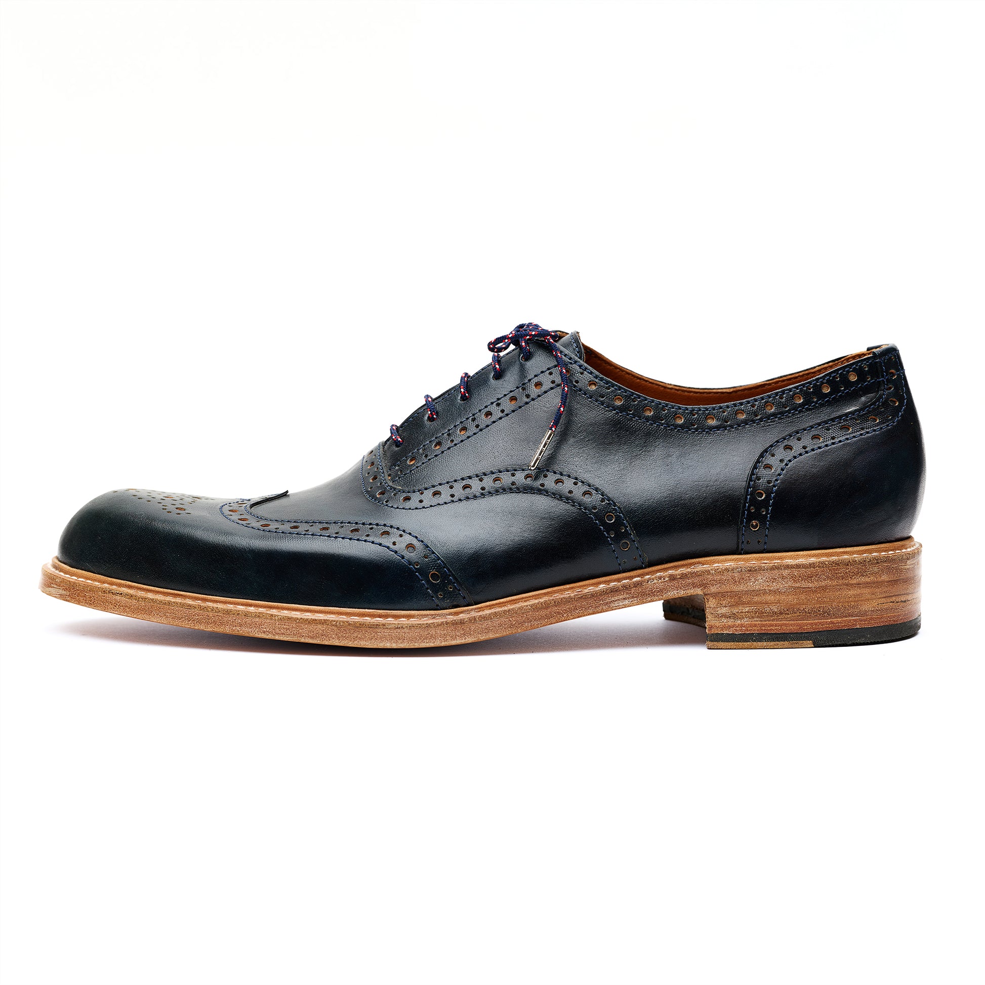 Pair of black leather brogue Oxford shoes with brown soles on white background. 