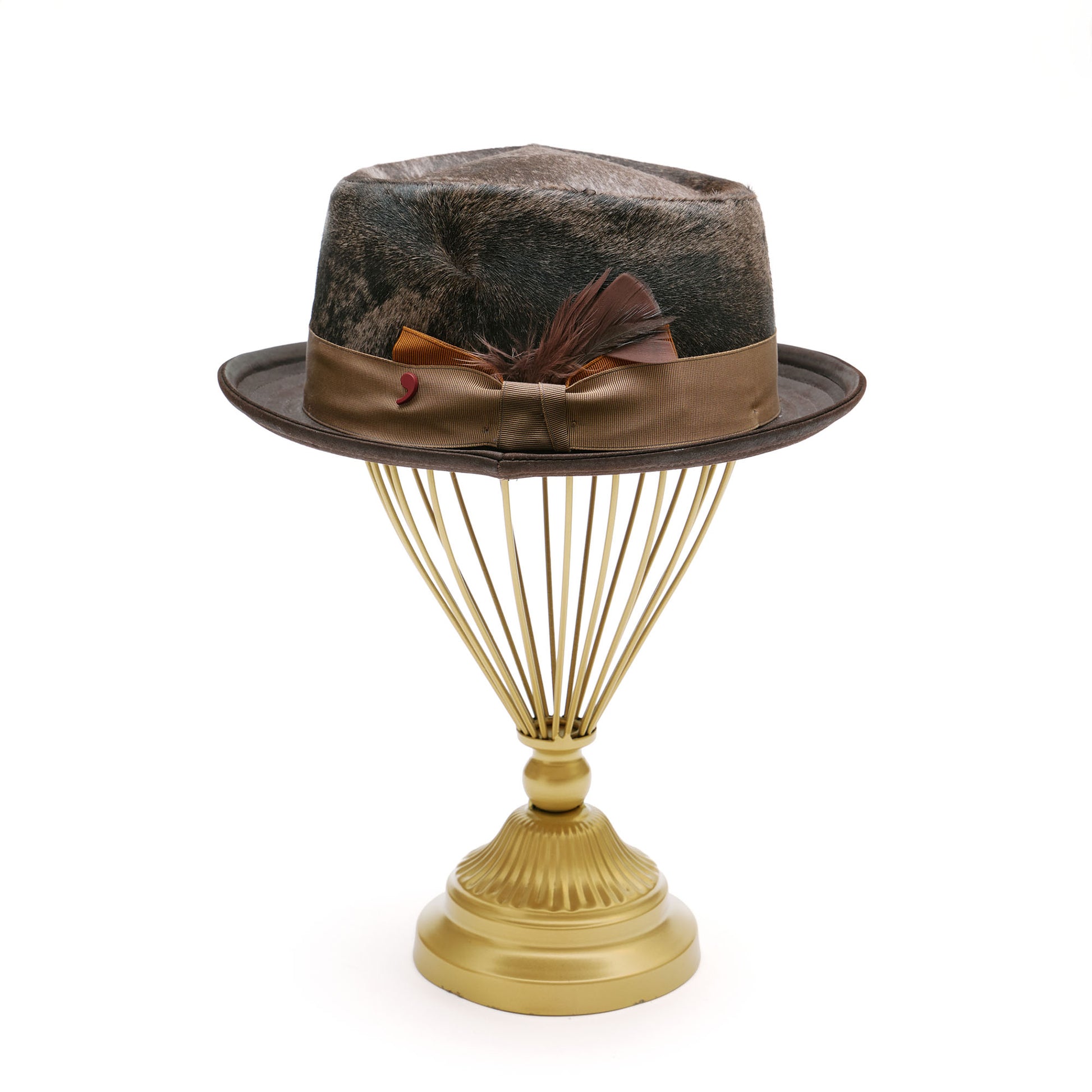 Brown fur porkie hat with feather on hat stand. 