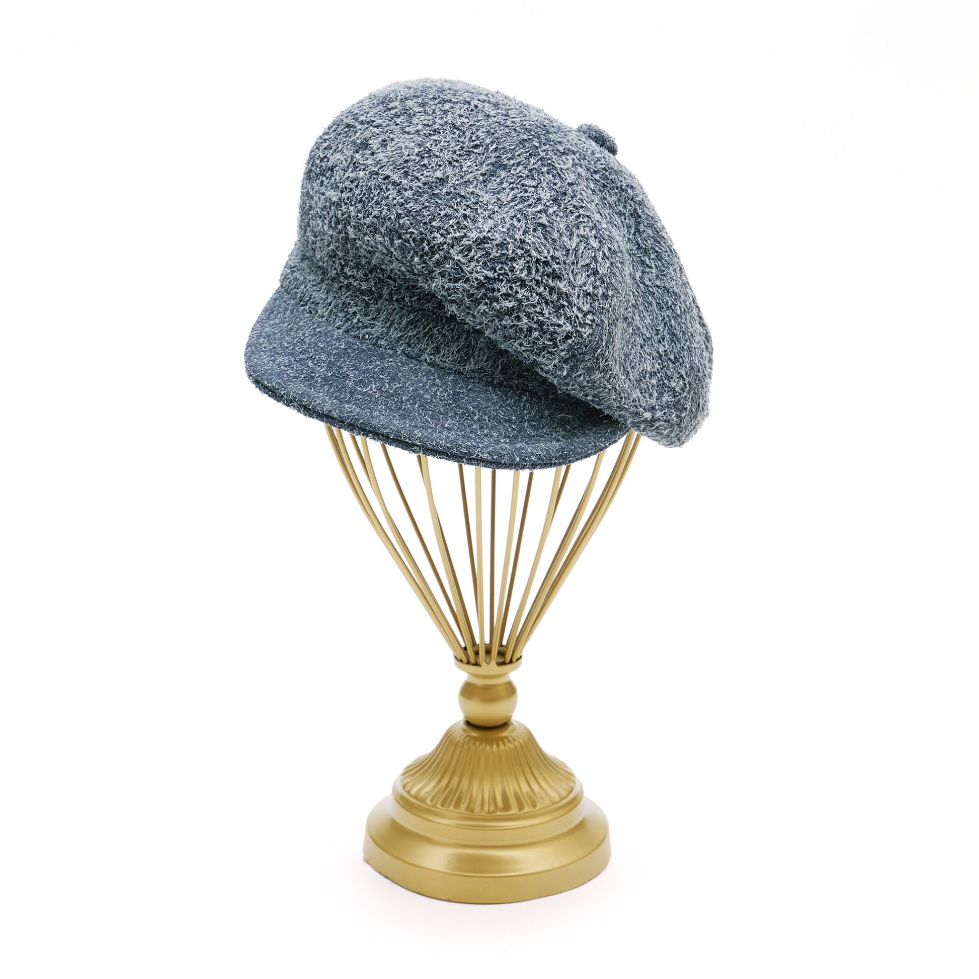 Grey suede melton cap on  gold hat stand in front of white background. 