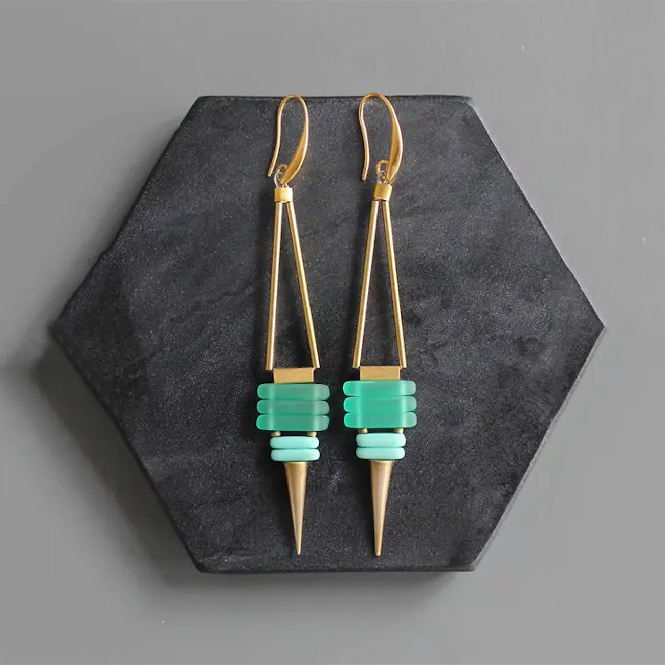 Check glass and brass spike earring on marble stone. 