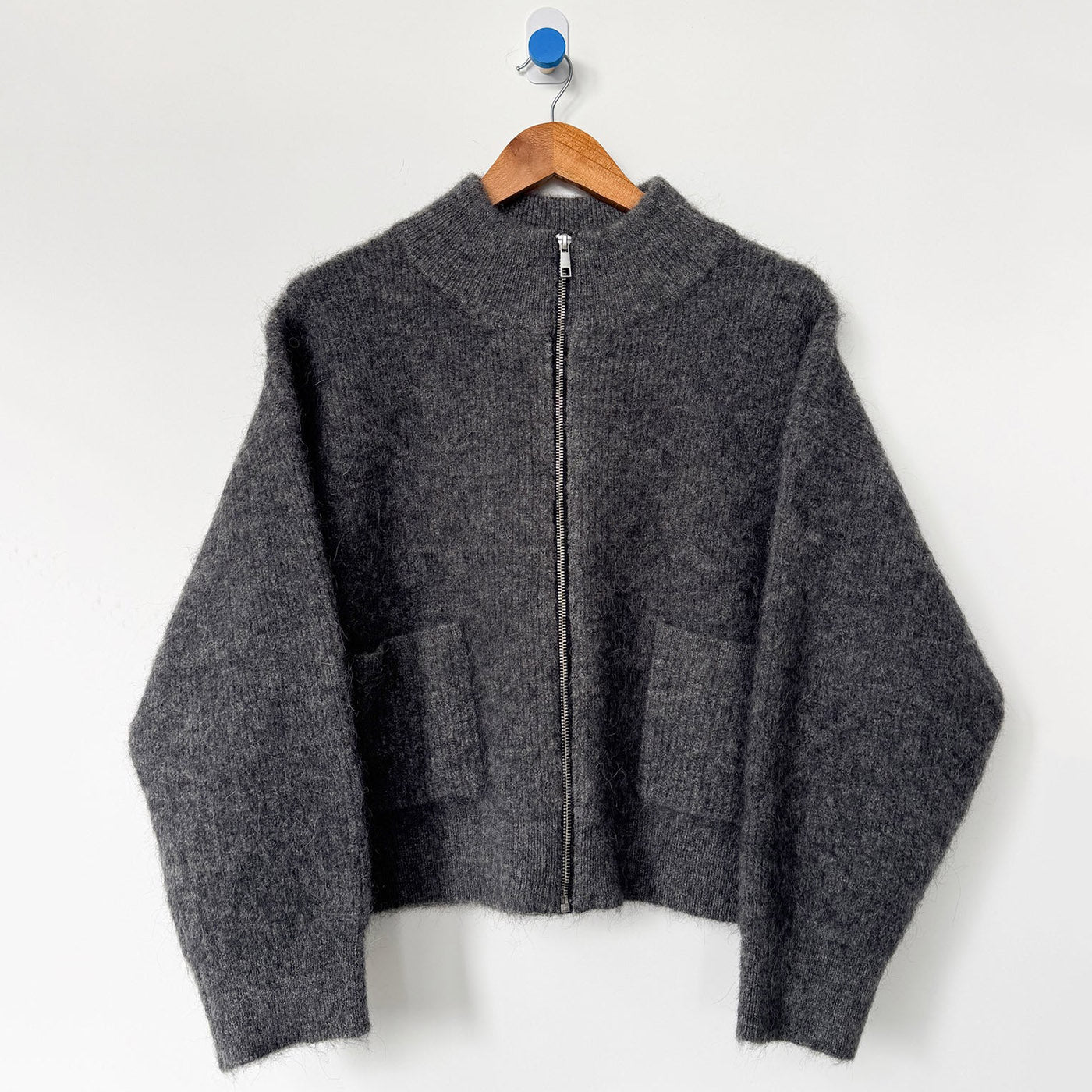 Dark grey Alpaca wool zip up sweater on wood hanger. 