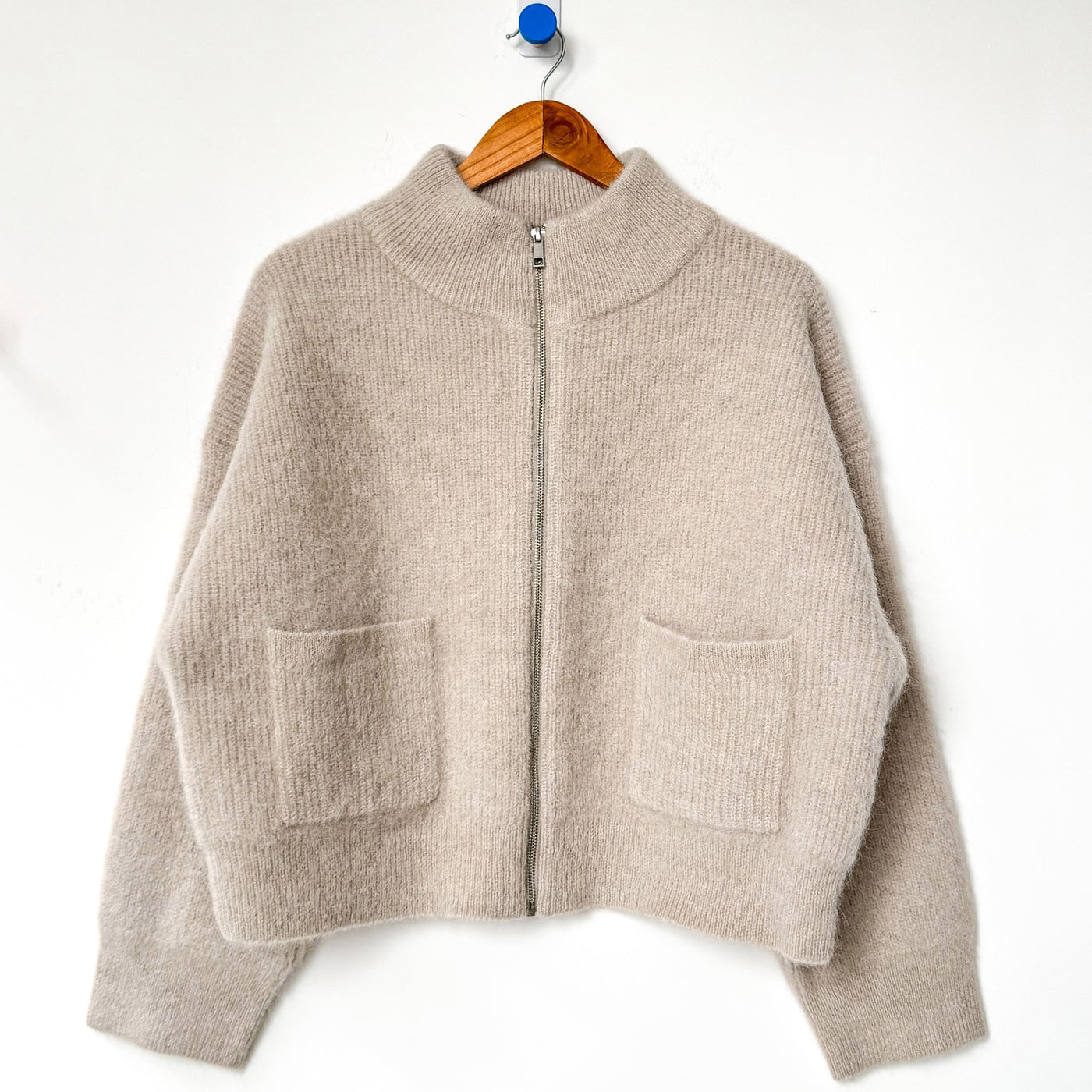 Light beige Alpaca wool zip up sweater on wood hanger. 