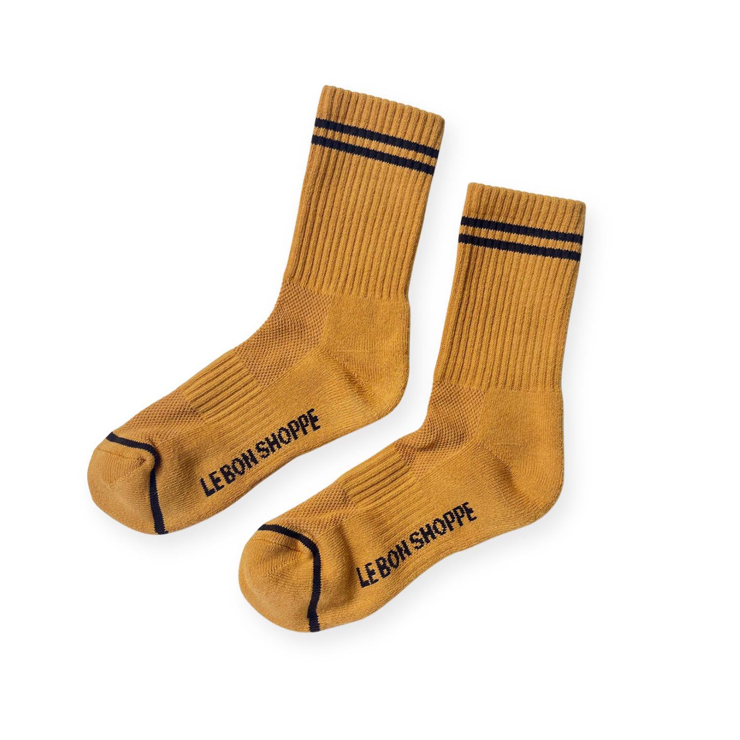 Pair of dark yellow ribbed sport socks with double black stripe around ankle and "Le Bon Shoppe" on soul. 