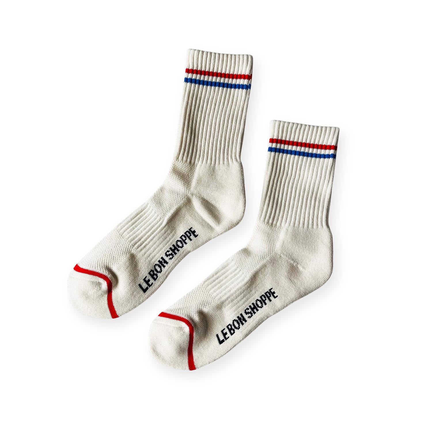 Pair of white ribbed sport socks with red and blue stripe around ankle and "Le Bon Shoppe" on soul. 