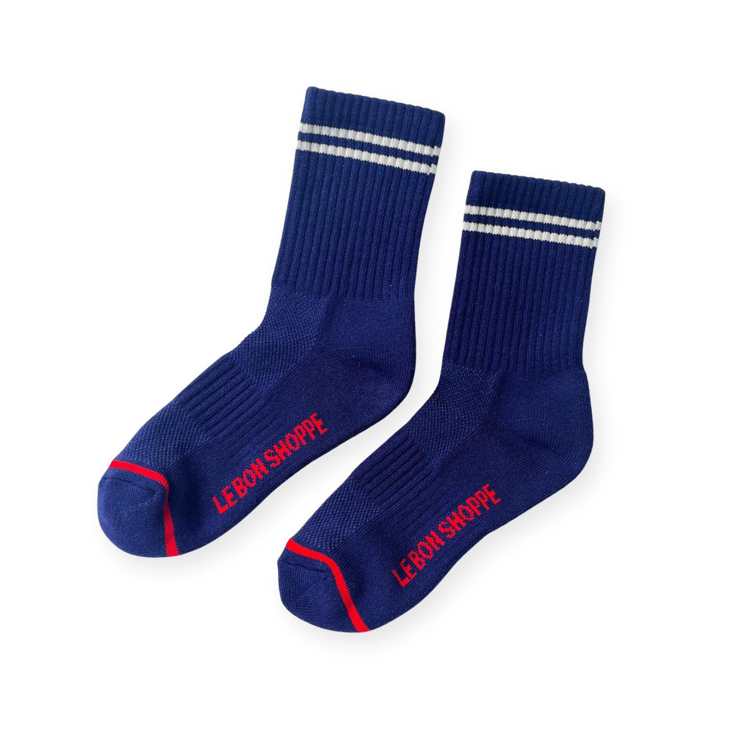 Pair of navy ribbed sport socks with double white stripe around ankle and "Le Bon Shoppe" on soul. 