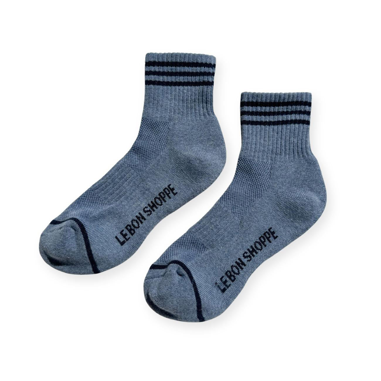 Pair of indigo sport socks with black stripes on ankle and Le Bon Shoppe text on soul. 
