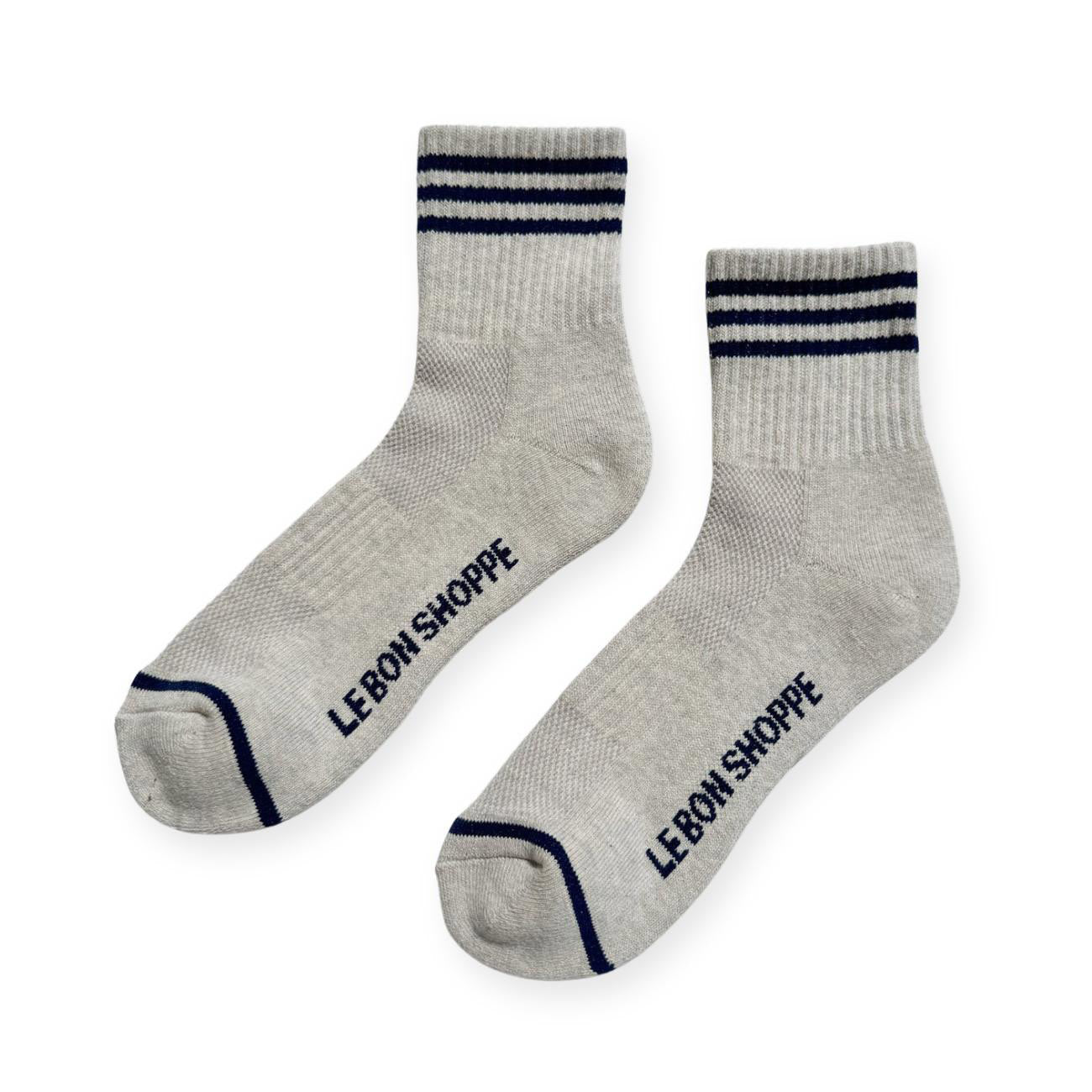 Pair of gray sport socks with black stripes on ankle and Le Bon Shoppe text on soul. 