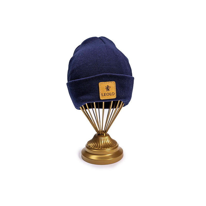 Navy blue ribbed beanie with leather Leolo patch on at stand. 