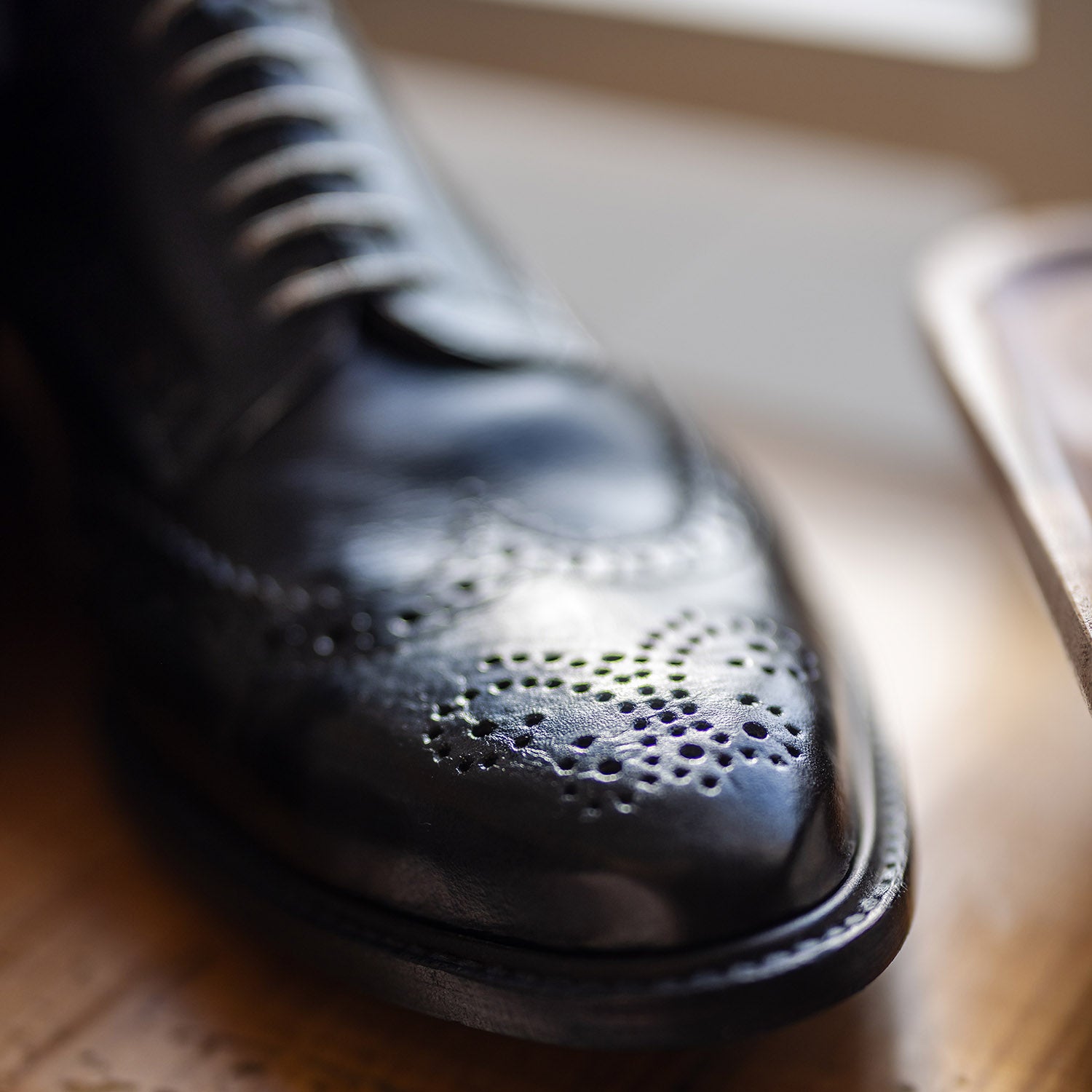 Close-up of black custom hand made leather oxford shoes by Leolo on wooden table. 