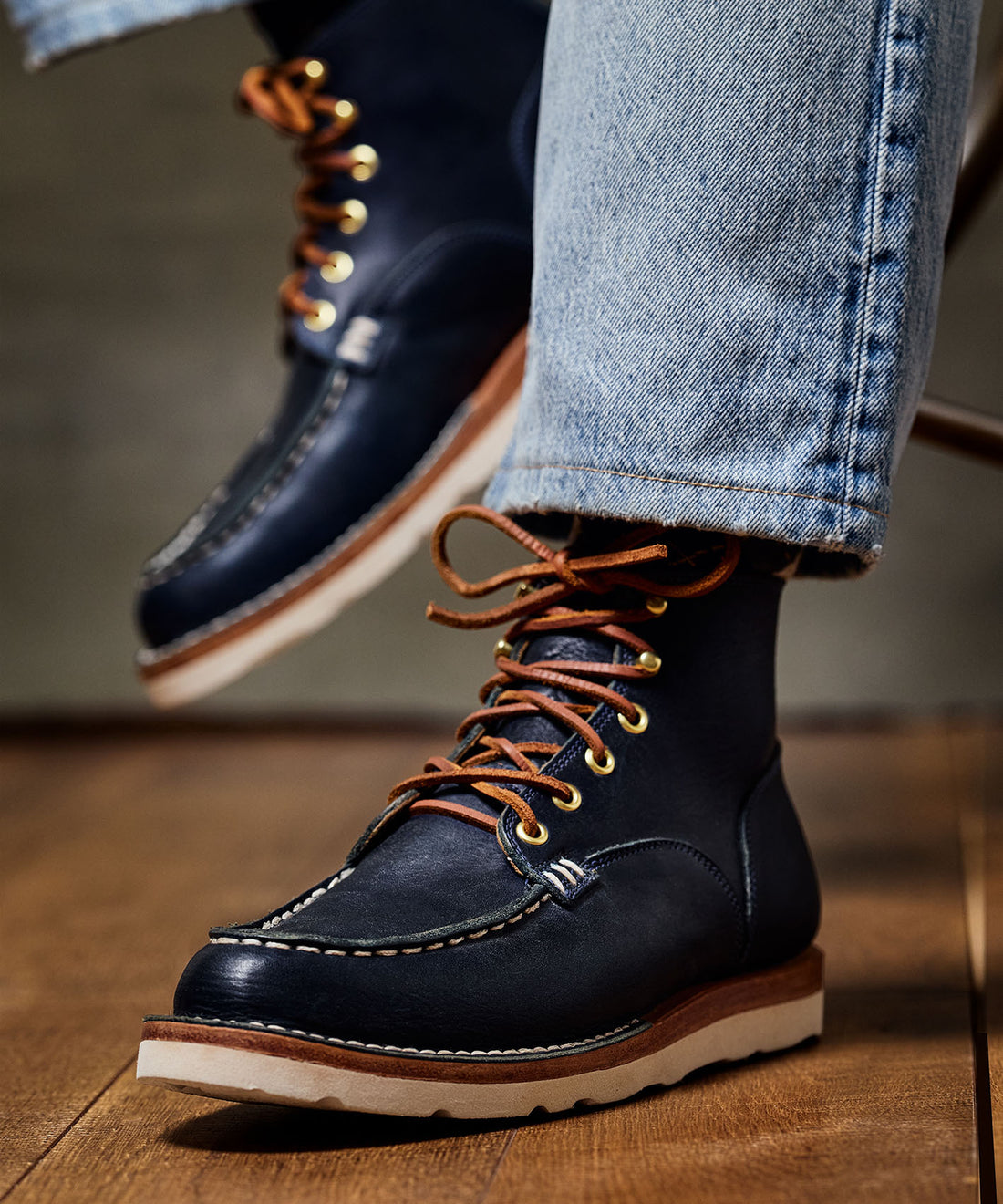 Close-up of man's legs wearing denim and black leather lace up work boots. 