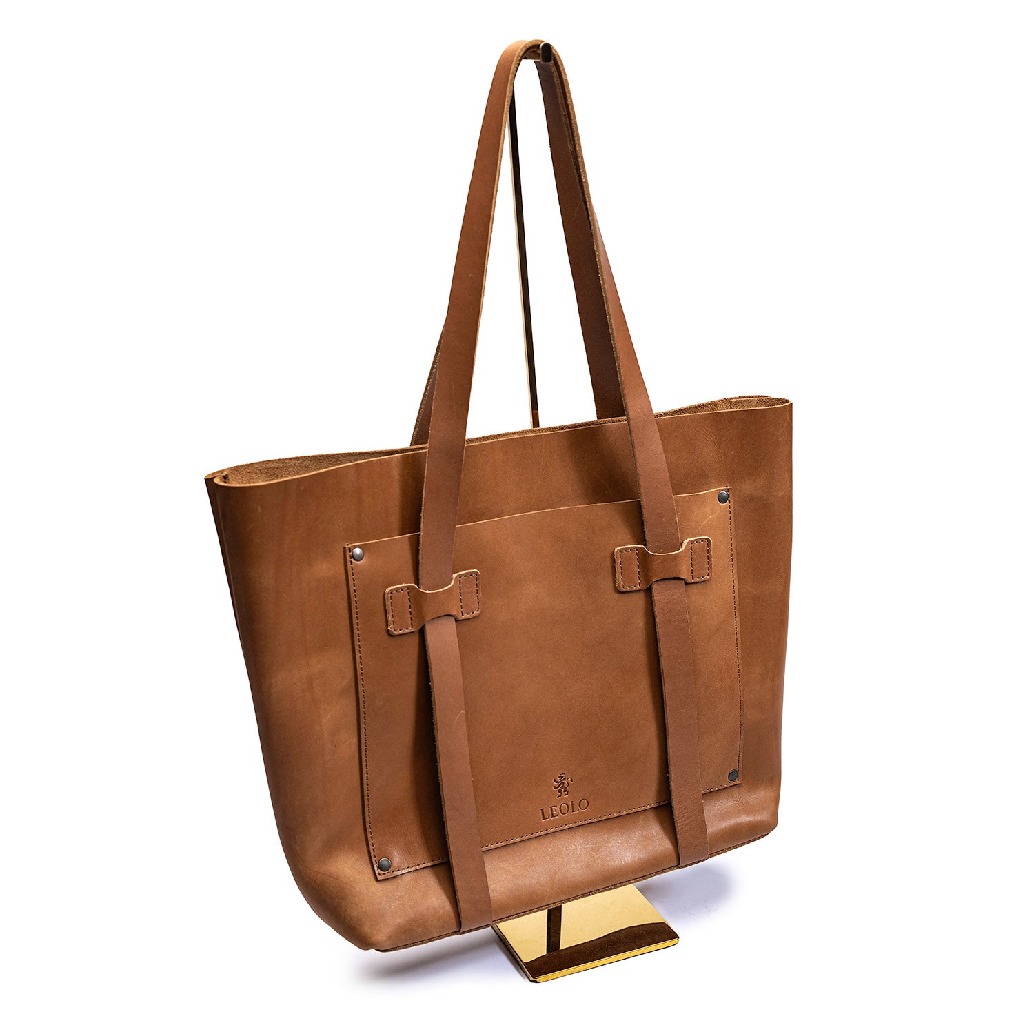 Brown leather market tote by Leolo, hanging on stand in front of white background. 