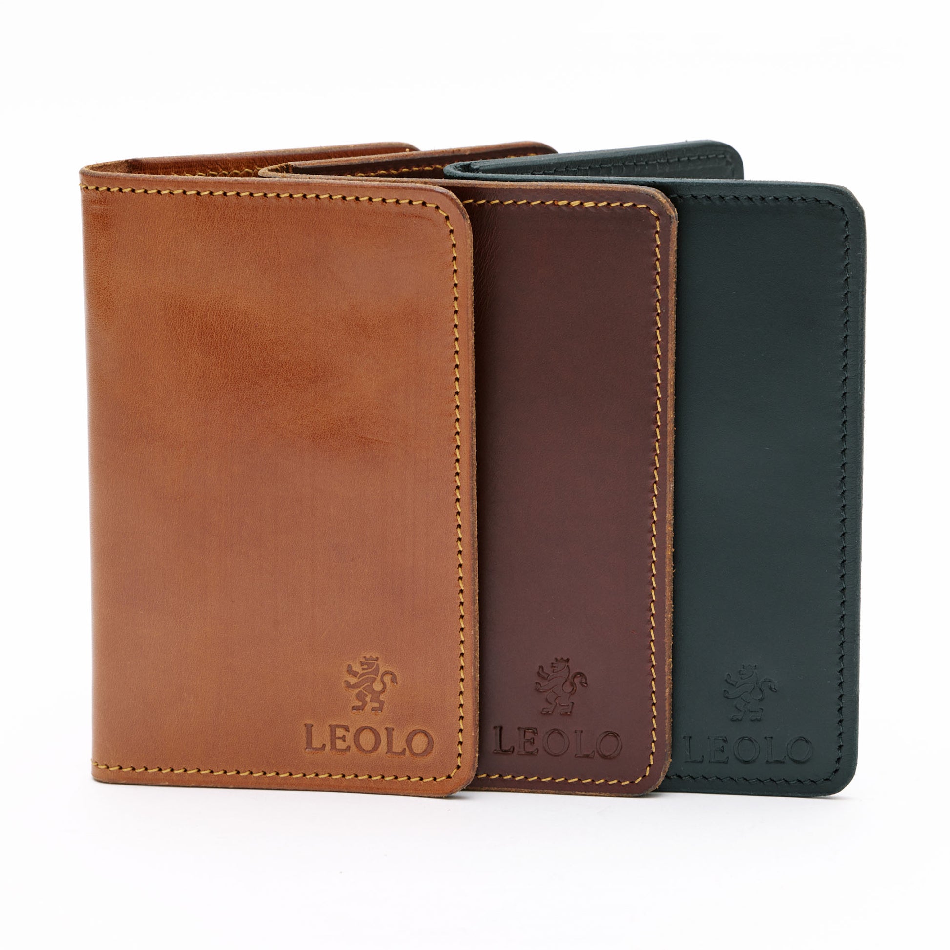 Three leather passport holders in tan, brown and black in front of white background.