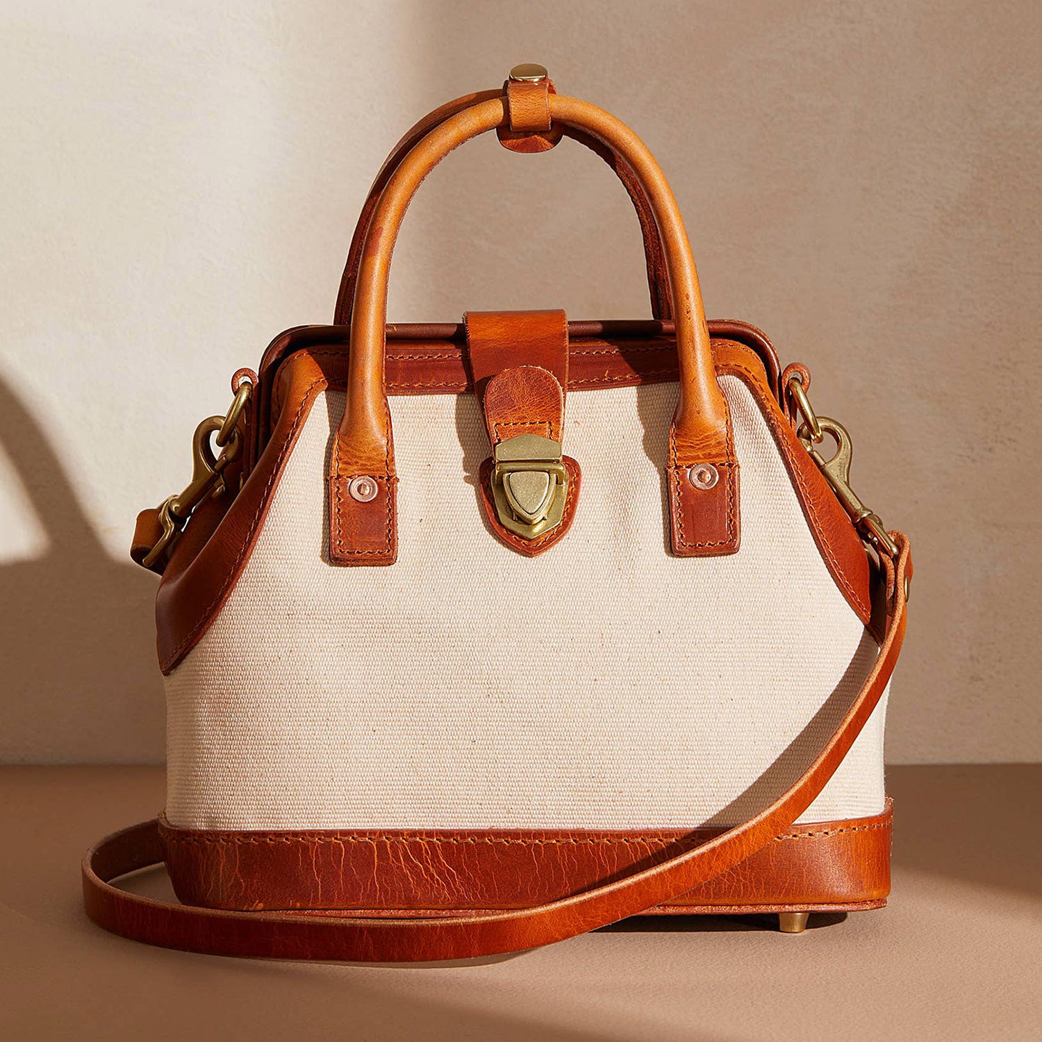 Cognac Italian leather and cream hemp canvas handbag by Uppdoo, with Japanese brass hardware. Bag is against a neutral background with shadow behind. 