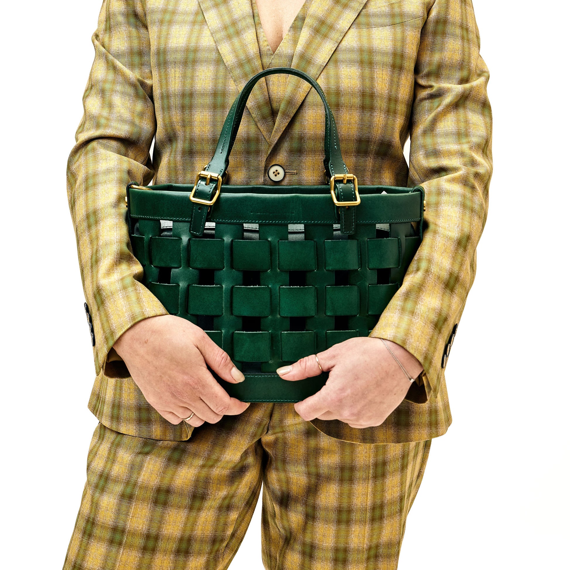 Person in plaid suit holding green basket weave style tote bag. 
