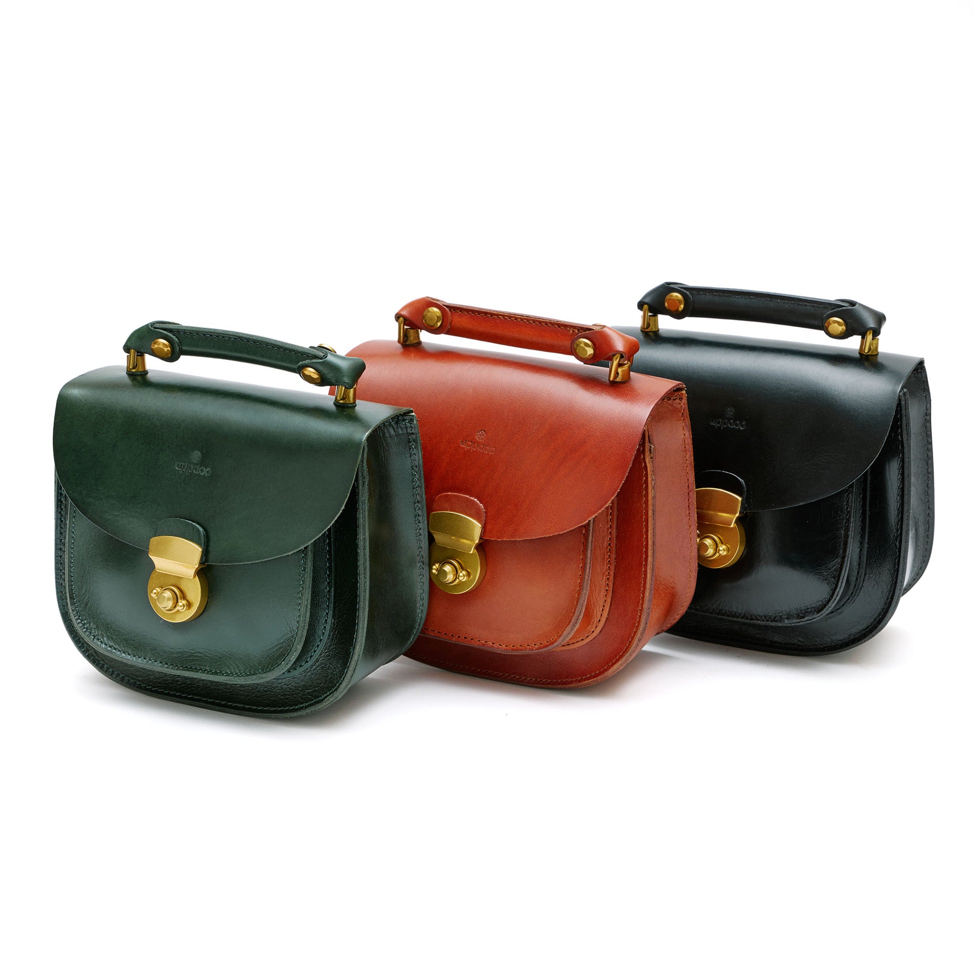 Three leather mini saddle handbags in black, brown and green leather with brass hardware. 