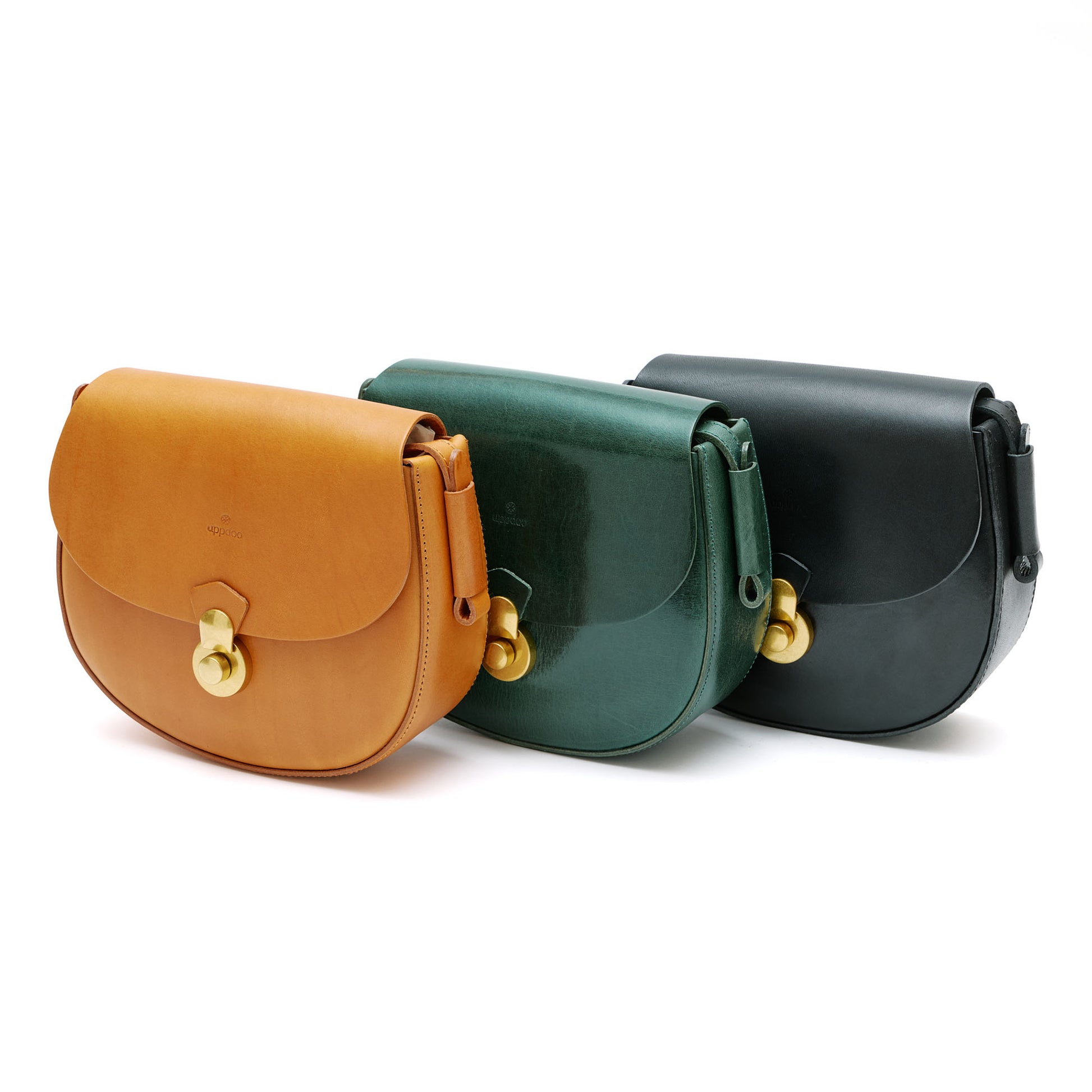 Three leather handbags in tan, green and black with gold hardware in front of white background. 